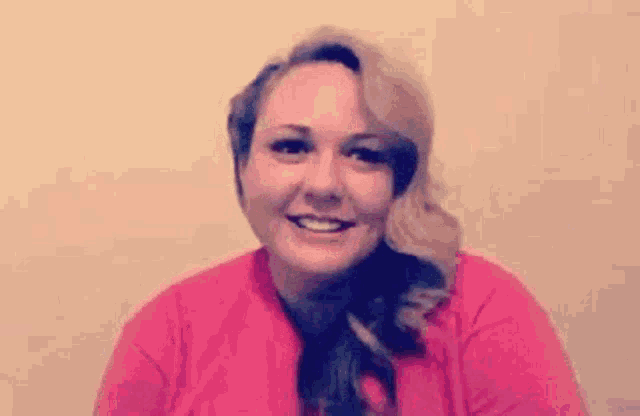 the woman is wearing a pink shirt and smiling .