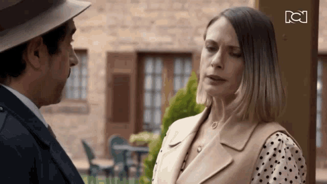 a man and a woman are standing next to each other and the woman has a polka dot shirt on