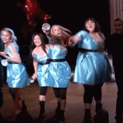 a group of women in blue dresses are standing on a stage with balloons in the background