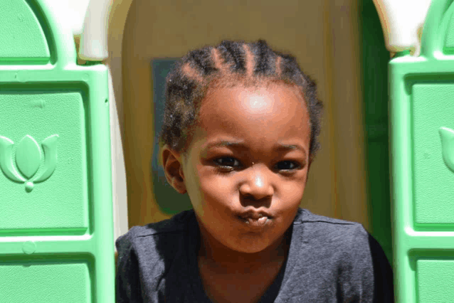 a young boy is making a funny face in a green playhouse