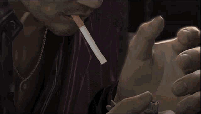 a man is lighting a cigarette with a lighter that says ' s ' on it