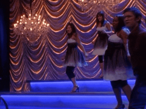 a group of women are dancing on a stage with blue lights