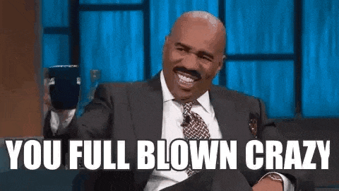 a man in a suit and tie is laughing and saying `` you full blown crazy '' while sitting down .