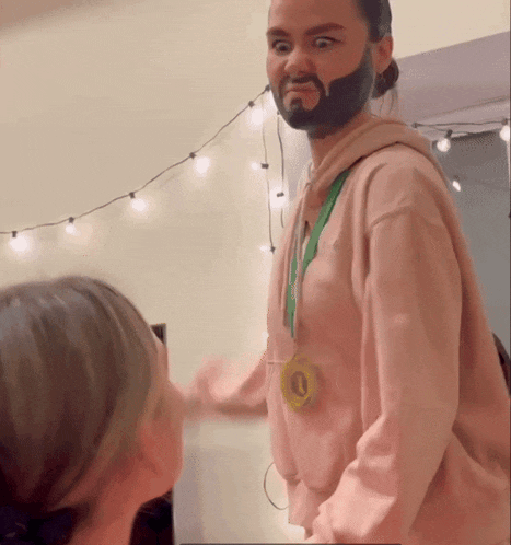 a man with a beard and a medal around his neck is wearing a pink sweatshirt