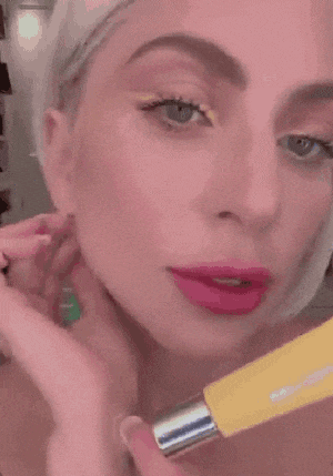 a close up of a woman applying lipstick to her lips