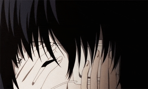 a person is covering their face with their hands in a dark room .