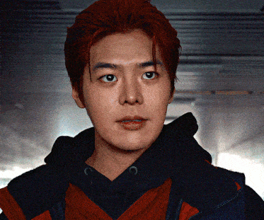 a man with red hair is wearing a black hoodie and a red jacket