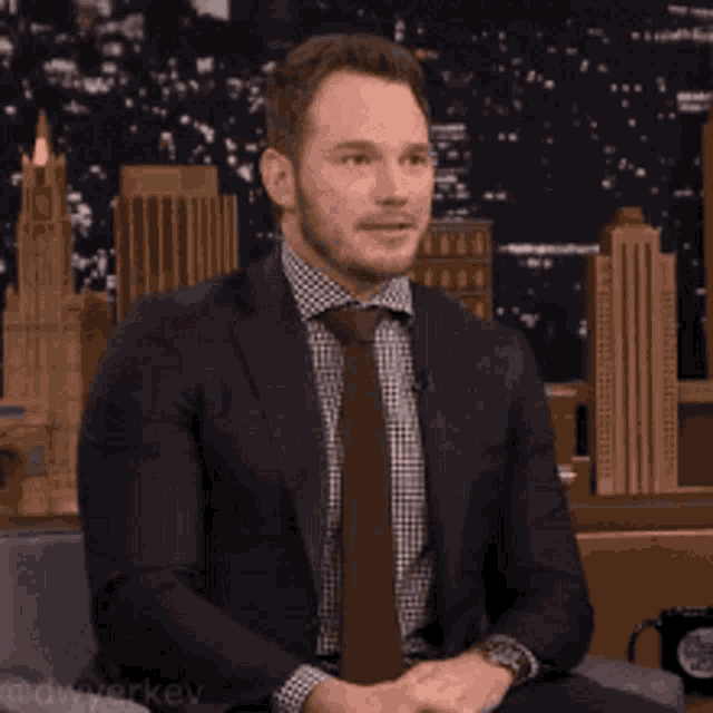 a man in a suit and tie is sitting down with his eyes closed