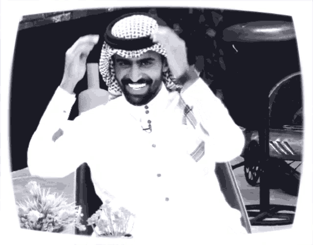 a black and white photo of a man wearing a head scarf and smiling