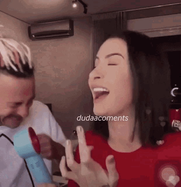 a man is blow drying a woman 's hair while she laughs .