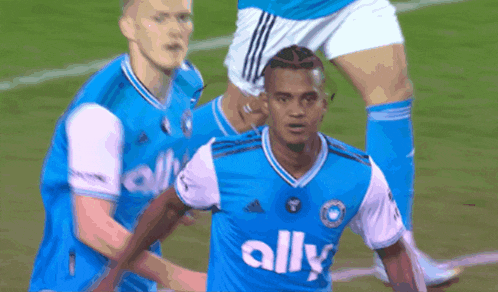 a soccer player wearing a blue jersey with ally on it