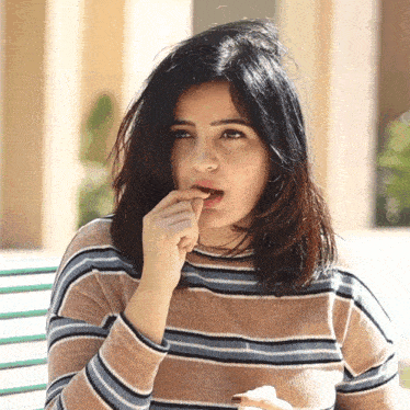 a woman in a striped sweater is biting her nails