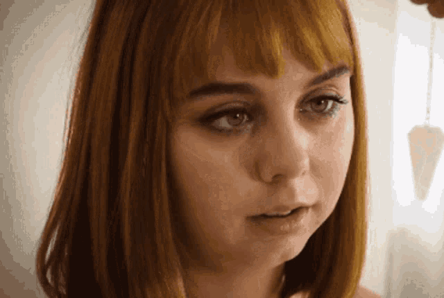 a close up of a woman 's face with a pendulum hanging from her hair