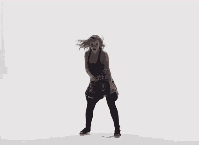 a woman wearing a black tank top and black tights is dancing