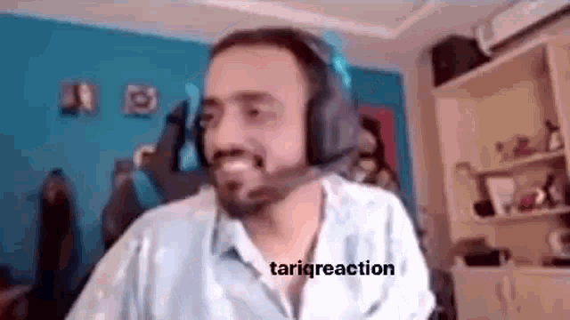 a man with a beard is wearing headphones and smiling while sitting in a room .