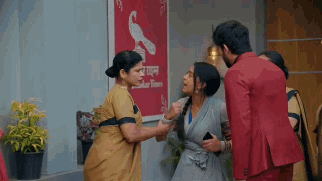 a man in a red suit is standing next to two women in front of a sign that says akbar times