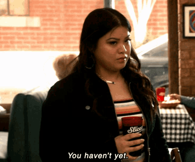 a woman in a black jacket holds a can of slice soda