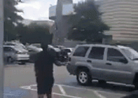 a man is standing in a parking lot next to a car .