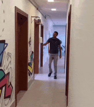 a man in a black shirt is walking down a hallway