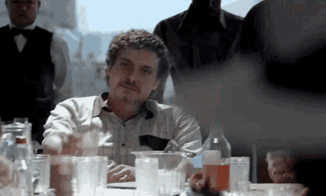 a man is sitting at a table with a lot of glasses and bottles