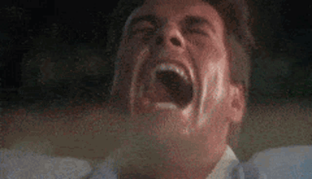 a close up of a man screaming with his mouth wide open .