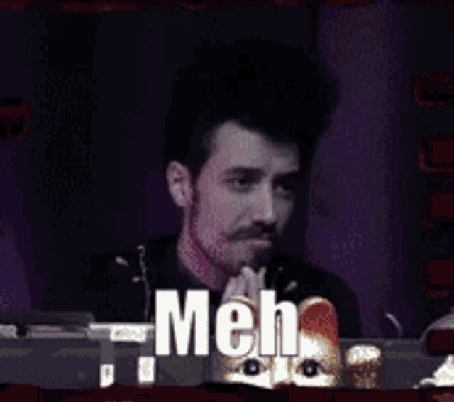 a man sitting in front of a microphone with the word meh on the screen