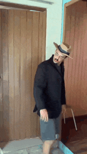 a man wearing a hat and mustache is standing in front of a door