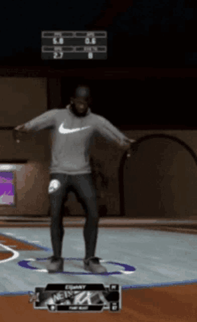 a man wearing a nike sweatshirt is standing on a basketball court