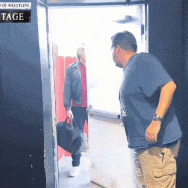 a man in a blue shirt is standing in front of a sign that says tage