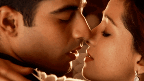 a close up of a man and woman kissing with their eyes closed