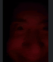 a close up of a person 's face in the dark with a red background .