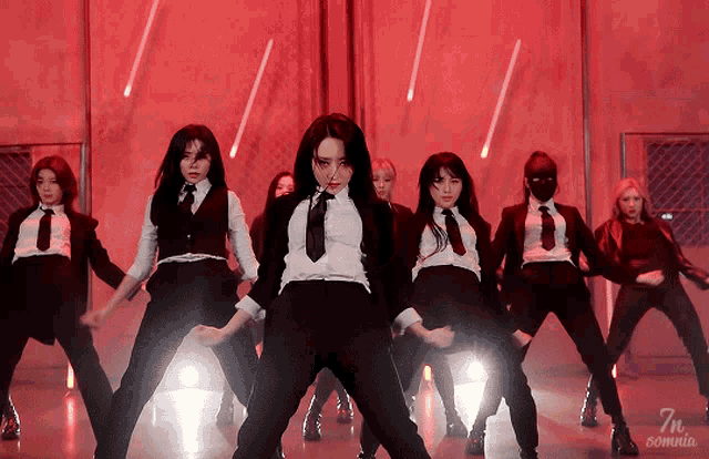 a group of women in suits and ties are dancing in front of a red background that says 7m somnia