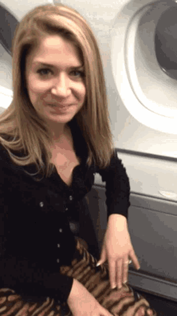 a woman wearing a black sweater and a ring is sitting on an airplane