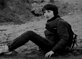 a young boy with a backpack is sitting on the ground .