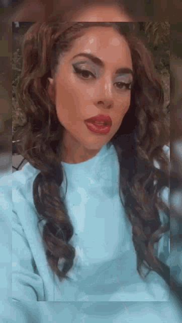 a close up of a woman 's face wearing a blue sweater and a blue eyeshadow .
