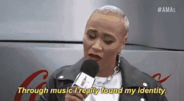 a woman is talking into a microphone and says `` through music i really found my identity . ''