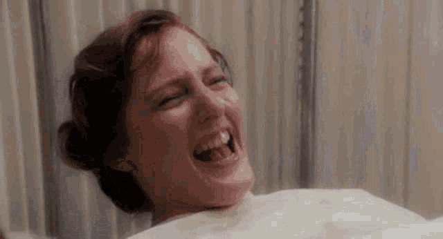 a woman in a hospital gown is laughing while giving birth .