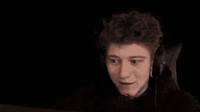 a young man wearing headphones is making a funny face while sitting in a chair .