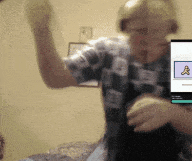 a man in a plaid shirt is dancing in front of a screen with a cartoon character on it