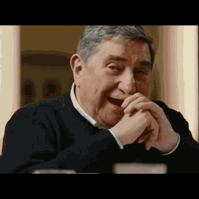 a man is laughing with his hands on his mouth