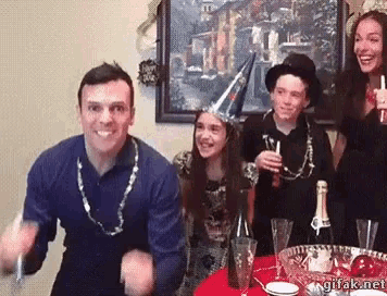 a group of people are sitting around a table with a bottle of champagne and glasses .