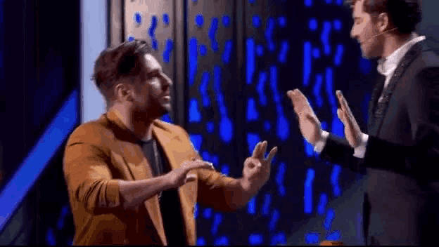 two men are standing next to each other on a stage and giving each other a high five .