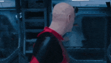 a man in a red and black superhero costume is standing in front of a mirror and looking at himself .