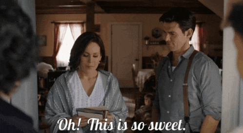 a man and a woman are standing in a room and the woman is holding a stack of books and says oh this is so sweet