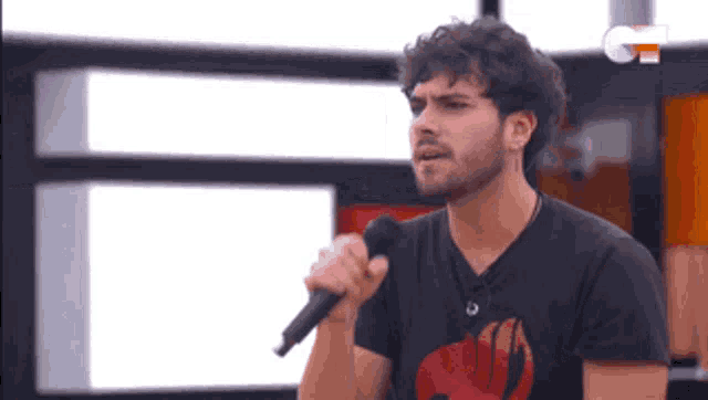 a man singing into a microphone while wearing a black shirt with fairy tail on it