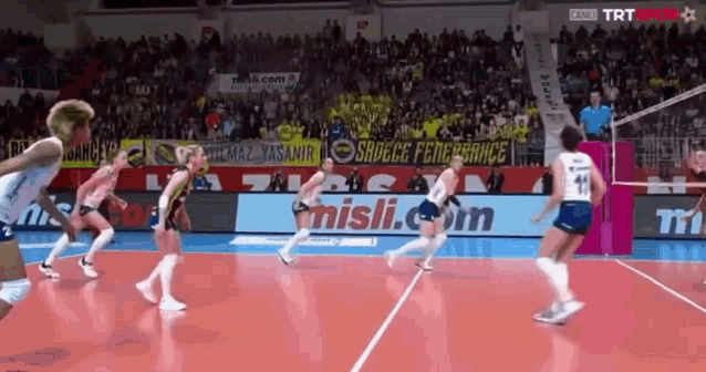 a volleyball game is being played in front of an advertisement for misli