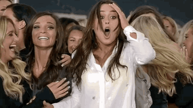 a group of women are standing next to each other and laughing .