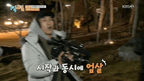 a man holding a camera with a kbs logo on the bottom right