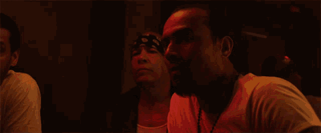 a man with a bandana on his head looks at another man