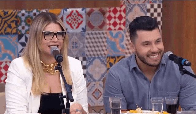 a woman singing into a microphone next to a man sitting at a table